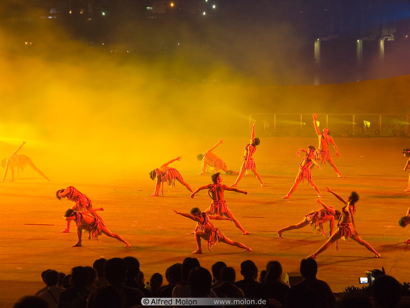 15 Dancers on stage illuminated with orange light