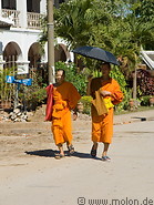 14 Buddhist monks walking with an umbrella