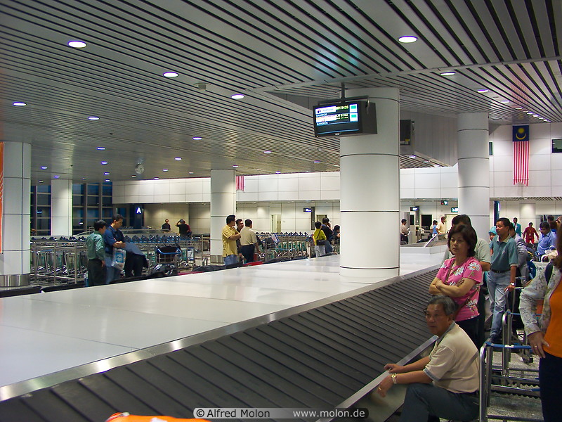 03 Travellers waiting at conveyor belt in arrivals area
