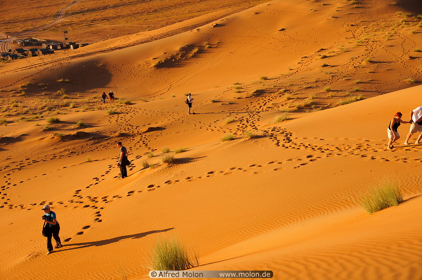 13 Tourists walking on sand dunes